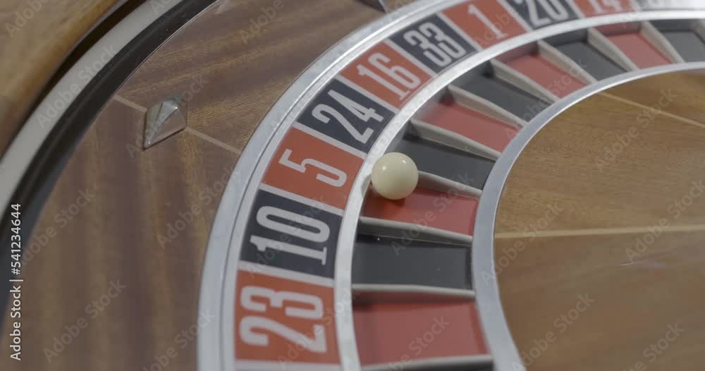 Spinning casino roulette with a ball in a red five slot close up Spinning casino roulette with a ball in a red five slot close up