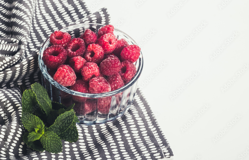 A bowl of fresh raspberries on a white background.