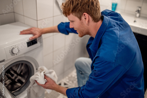 Man putting unfresh clolthes into the washing machine © zinkevych