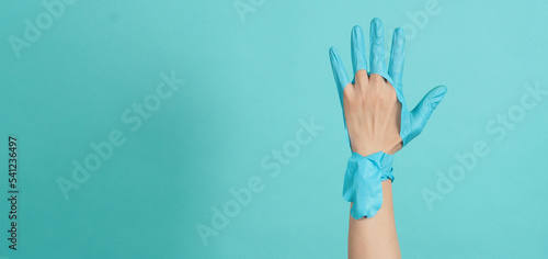 Fotografía Hand Wearing torn medical gloves or torn rubber gloves on blue or mint green bac