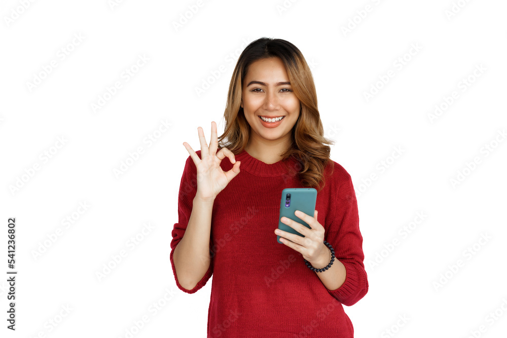 Using mobile, Excited young brunette pretty asian woman isolated on white background, red sweater. Using mobile, Excited young brunette pretty asian woman isolated on white background, red sweater.