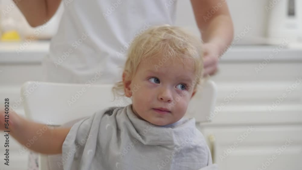 Mother cuts baby hair with clipper, little toddler boy getting haircut by his parent at home. Mother cuts baby hair with clipper, little toddler boy getting haircut by his parent at home.
