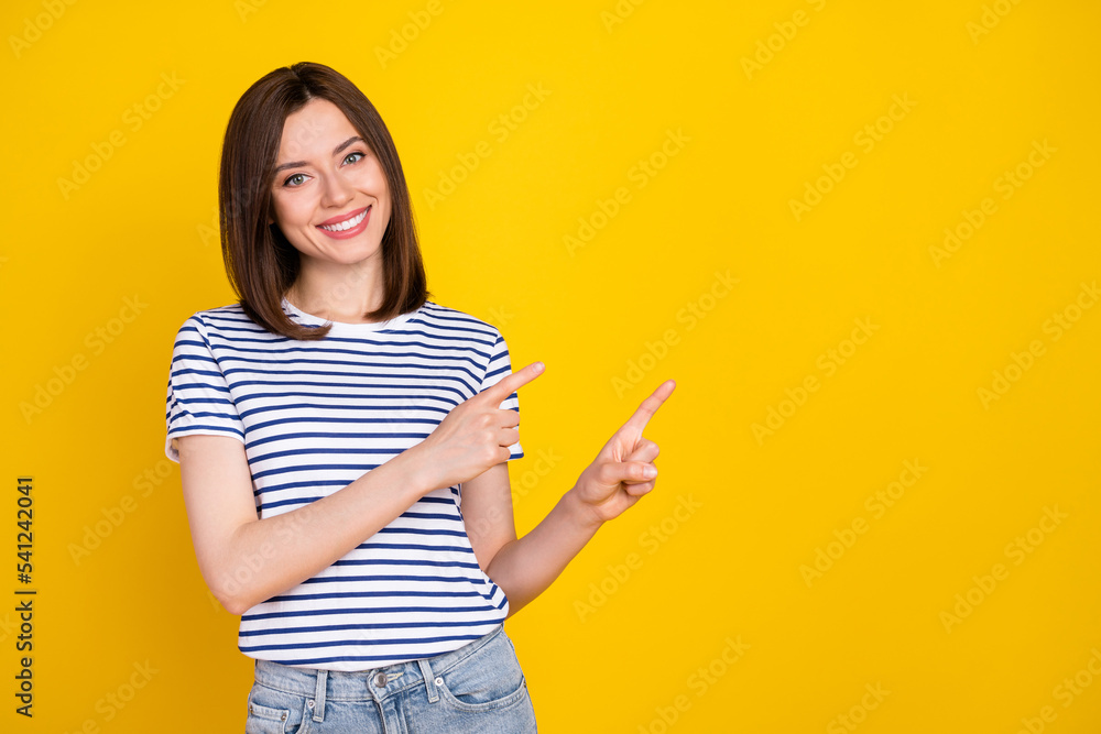 Photo of positive cheerful cute girl bob hairstyle wear striped t-shirt directing empty space shopping isolated on yellow color background Photo of positive cheerful cute girl bob hairstyle wear striped t-shirt directing empty space shopping isolated on yellow color background
