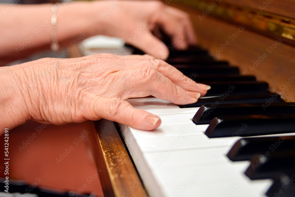 Obraz premium Close-up shot of an elderly menopausal woman playing the piano as a hobby in a nursing home 