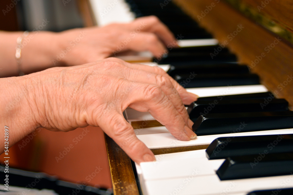 Obraz premium Close-up shot of an elderly menopausal woman playing the piano as a hobby in a nursing home 