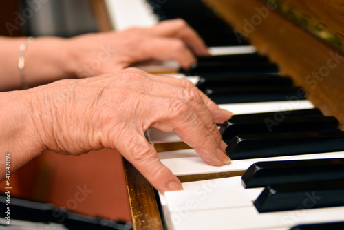 Close-up shot of an elderly menopausal woman playing the piano as a hobby in a nursing home 