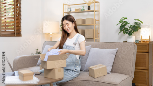 Woman is packing in the mailbox to prepare to deliver it to the customer, Working at home and owning businesses, Online shopping SME entrepreneur, Packing box, Sell online, Freelance working. © Puwasit Inyavileart