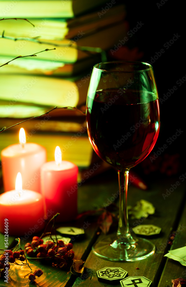 A glass of steaming wine on the table next to books and candles A glass of steaming wine on the table next to books and candles