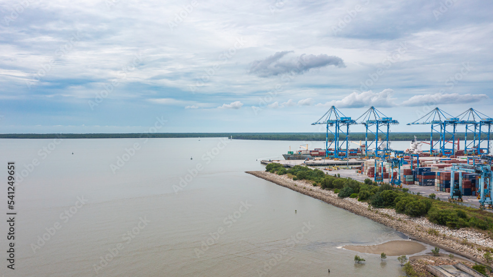 Klang, Malaysia - October 09, 2022: Cranes at the port Klang near Kuala Lumpur. Container crane at Klang Harbor. Aerial view on a container ship which is being loaded. Heavy Trucks at the Cargo bay