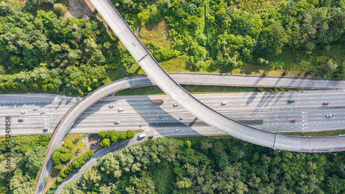Aerial view directly above a six lane highway. Top view of asphalt road passes through the field and forest. Aerial. Sedan cars driving by the highway. Top view from drone. aerial photo autobahn road photo