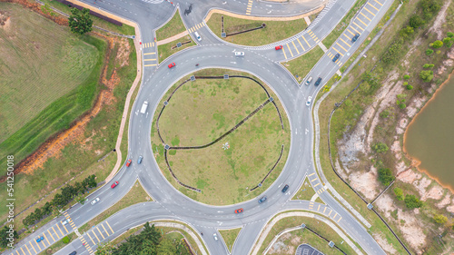 Aerial top down view of traffic roundabout on a main road. Aerial view of roundabout in the city in the summer. Aerial view of traffic infrastructure. Sedan cars moving over the asphalt. Road crossing
