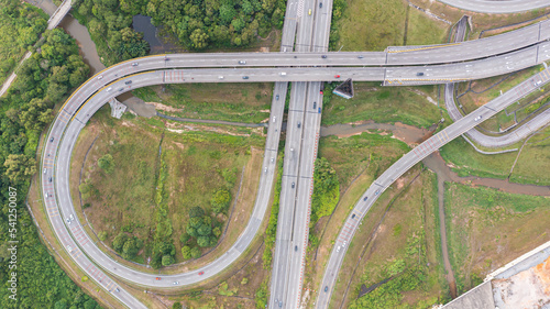 Aerial view of highway and overpass in city on a sunny day. Road traffic in city at Malaysia. Aerial view at junctions of city highway. Vehicles drive on roads. Top view of vehicles driving on street