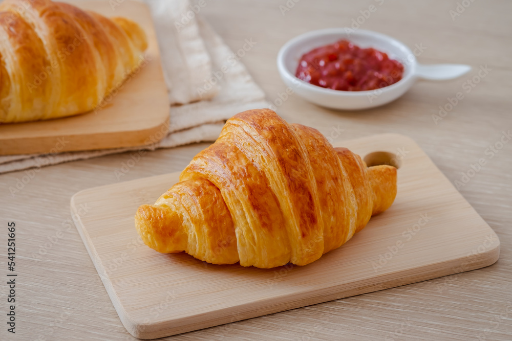 Fresh croissant on wooden board and jam on table Fresh croissant on wooden board and jam on table