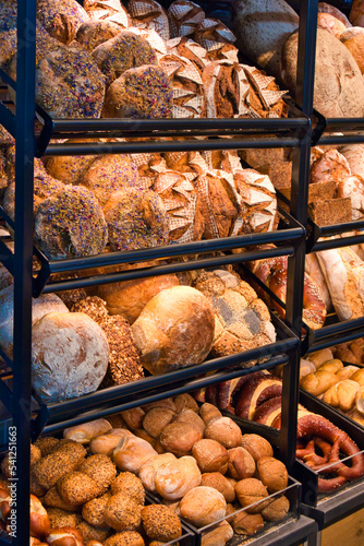 Bakery shop display. Bakery shop with different products. Bakery products on display. Shelves with different sorts of bread, buns and pretzels. Beautiful shop display of baked products. Tasty display.