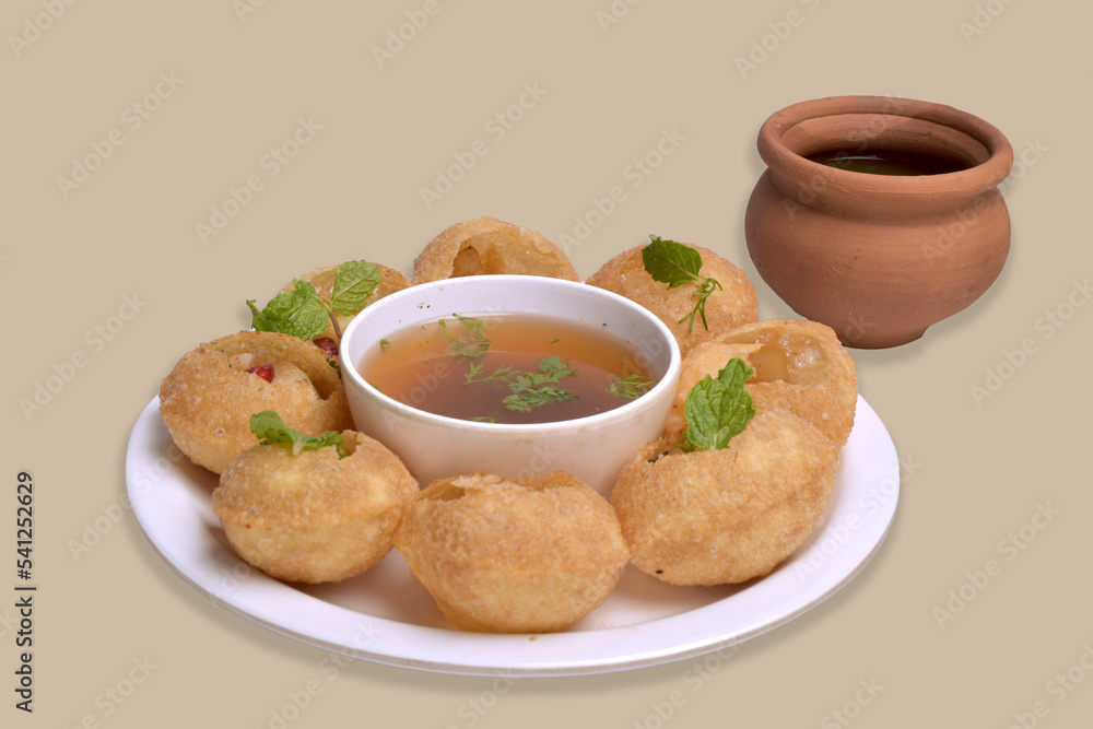 Delicious north and south indian street food pani puri gol gappa with tamarind water served in white plate and mud pot with potato and chickpeas