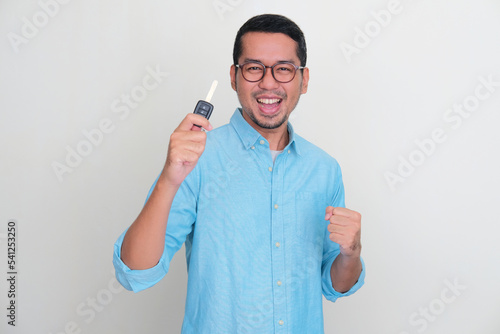Adult Asian man holding car key with excited expression photo