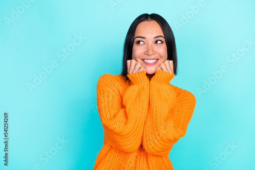 Photo of adorable optimistic woman with straight hairdo dressed orange pullover look empty space isolated on teal color background © deagreez