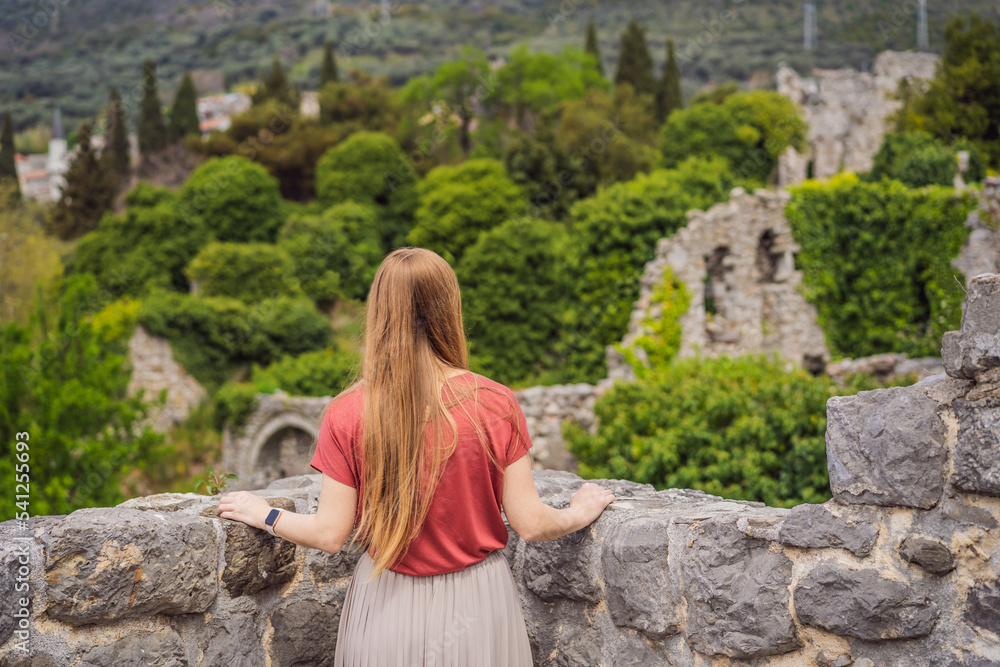 Fototapeta premium Woman tourist walks through the old town of Bar in Montenegro. Happy tourist walks in the mountains. Suburbs of the city of Bar, Montenegro, Balkans. Beautiful nature and landscape