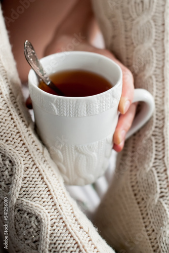 Hand holding a cup of tea with a knitted pattern that matches the socks