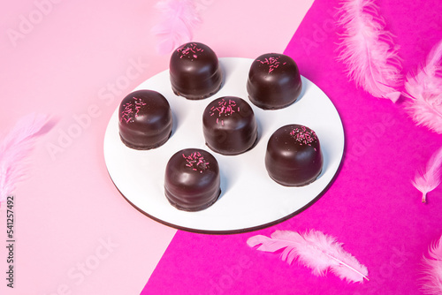 Sponge marshmallow candy covered in chocolate and vanilla wafer underneath, on a pink background. photo