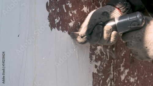 Pneumatic hammer beats pieces of old paint off the wall.