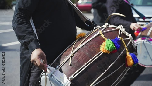Close-up hands of Indian man playing Indianmusical instrument Dhol drum using two wooden sticks