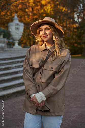 beautiful young woman in a hat in a sunbeam in autumn park