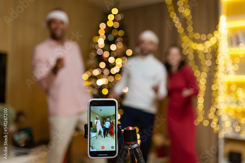 funny friends record reels stories front smartphone camera for social networks during New Year holidays party Christmas Eve celebration. Having fun dancing look pose at camera at home guys having fun photo