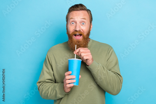 Portrait of positive impressed handsome man with red hairstyle wear khaki pullover hold takeaway cup isolated on blue color background