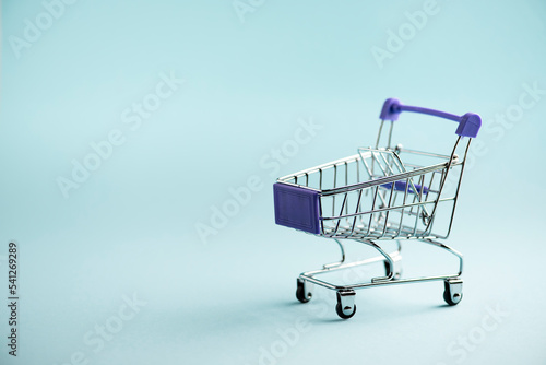 Pastel miniature shopping cart on blue background