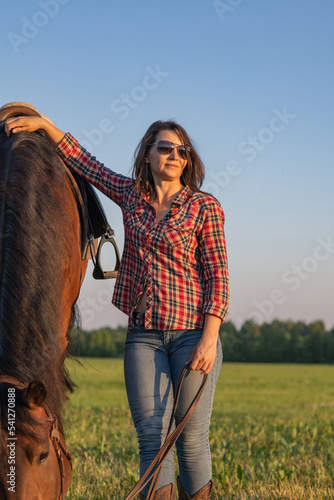 Portrait of a young beautiful girl in a field next to a horse.