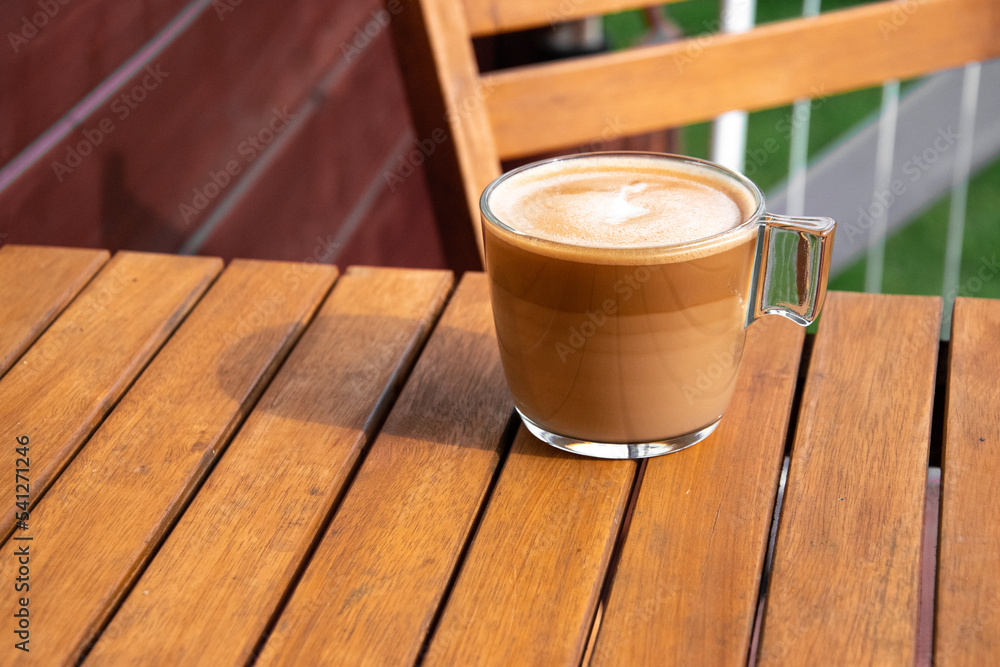 Fresh coffee on a wooden table during breakfast. The sun falls on the cup. Time to relax