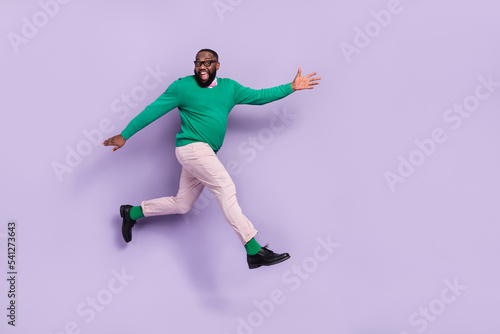 Full body image of good mood energetic young man running forward go on walk isolated on purple color background