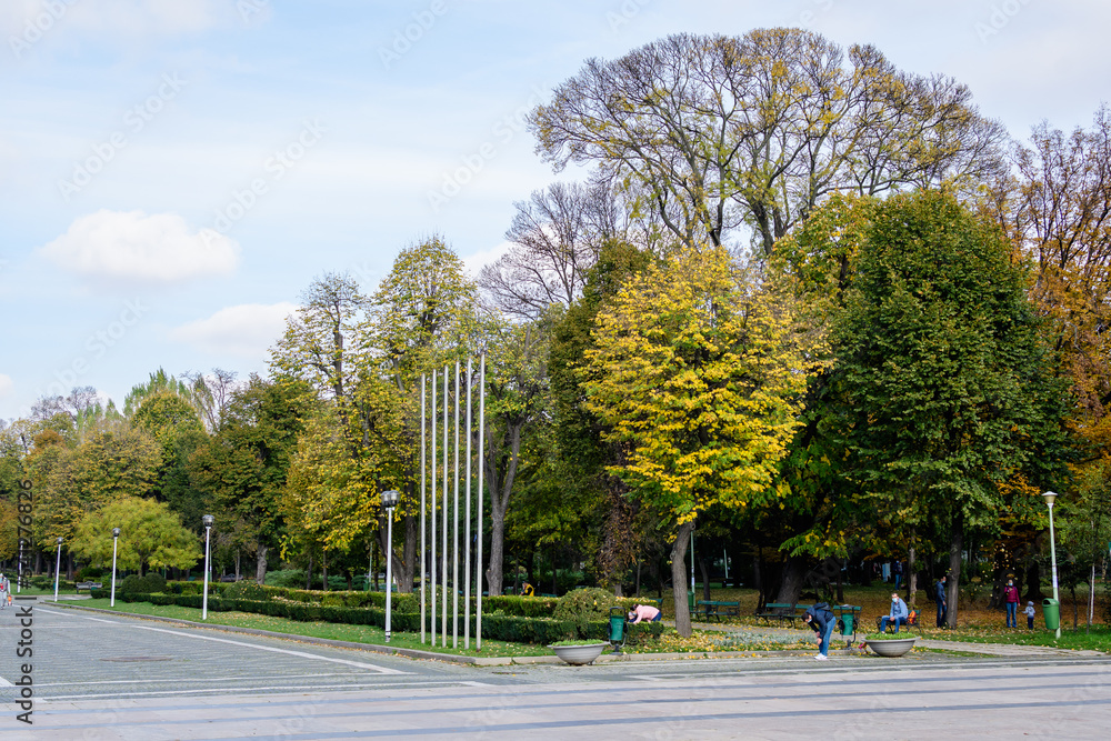 Landscape with old trees with green and yellow leaves in a sunny autumn day in Parcul Carol (Carol Park) in Bucharest, Romania . Landscape with old trees with green and yellow leaves in a sunny autumn day in Parcul Carol (Carol Park) in Bucharest, Romania .