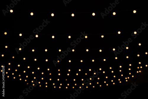 Abstract Christmas lights on black background. Glowing light bulb garland,