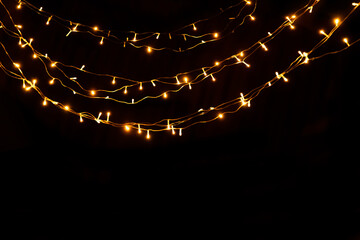 Abstract Christmas lights on black background. Glowing light bulb garland,