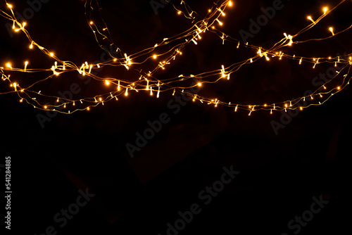 Abstract Christmas lights on black background. Glowing light bulb garland,