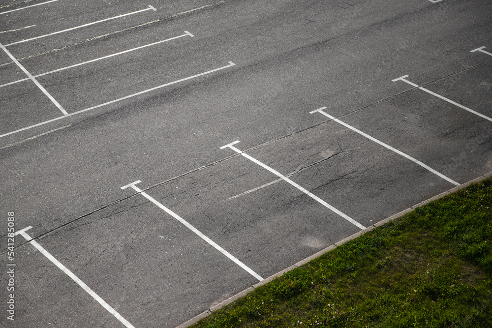 Empty parking lot, white road marking lines go over gray asphalt