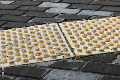 Street pavement with gray bricks and yellow tactile warning plates