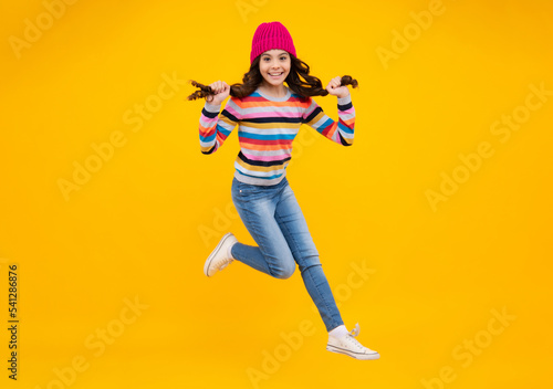 Amazed teenager. School girl in winter clothes and warm hat. Jump and run. Winter holiday vacation. Child fashion model. Excited teen girl.