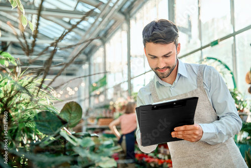 male florist taking notes on the clipboard.