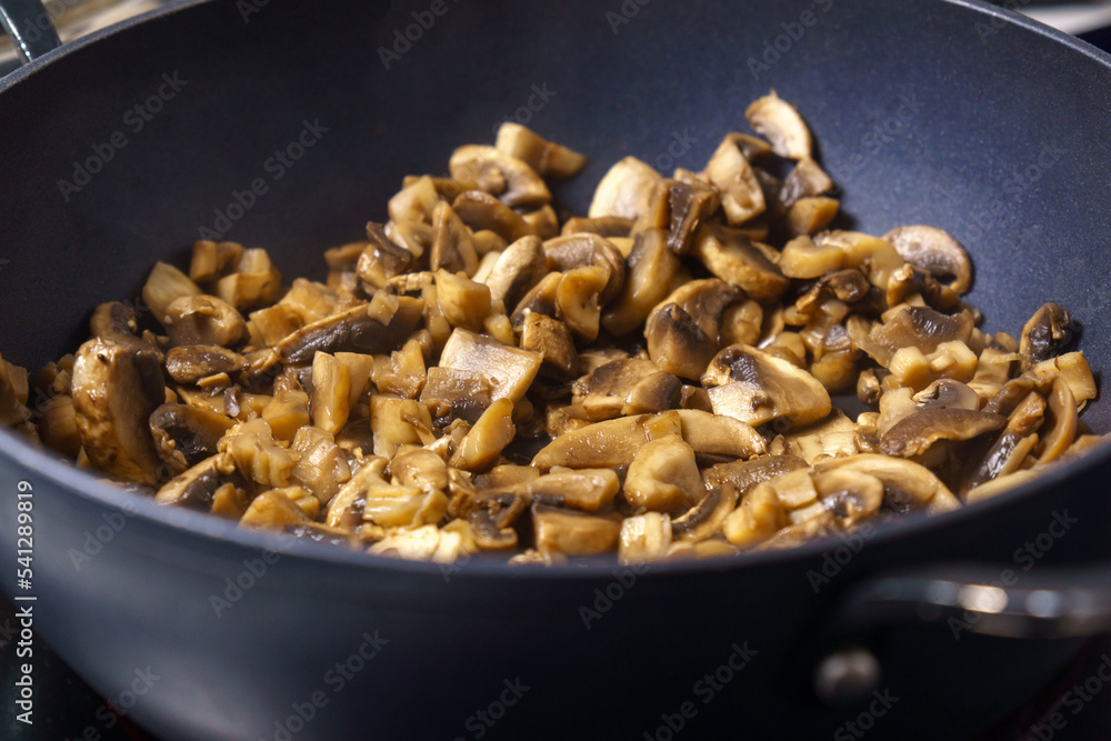 Cooking fried mushrooms, champignons in a pan. Close-up. Selective focus Cooking fried mushrooms, champignons in a pan. Close-up. Selective focus