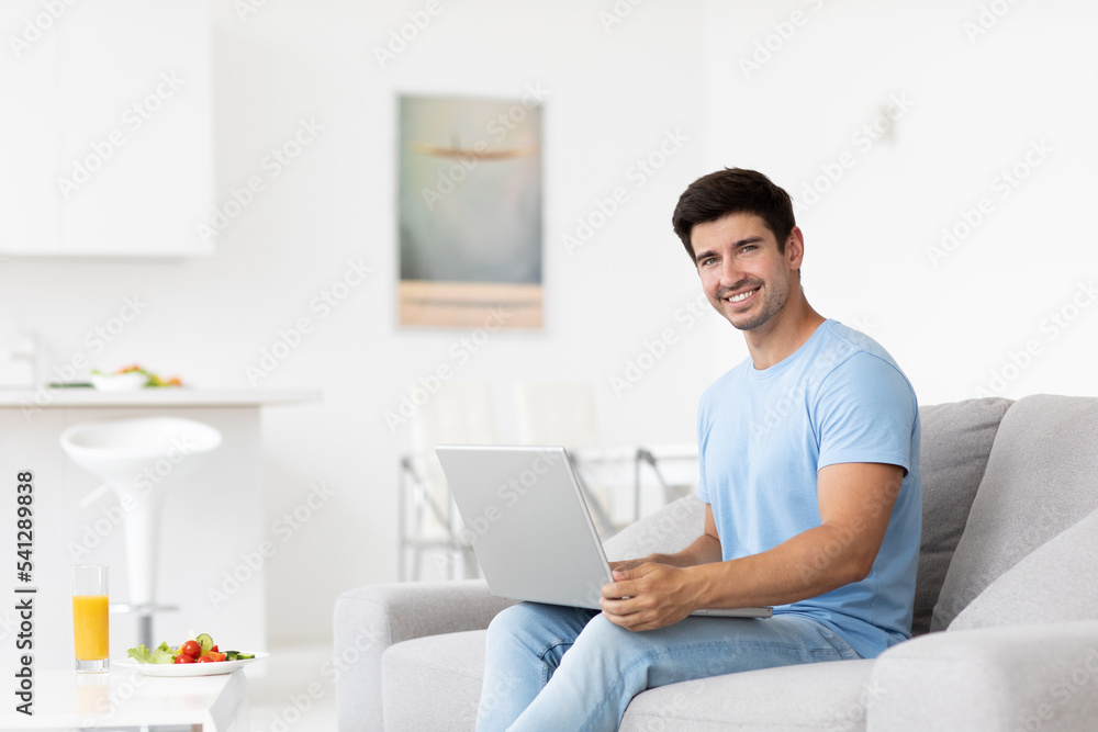 Young smiling man with laptop at home Young smiling man with laptop at home