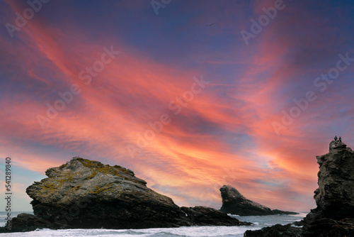 Pareja sentada sobre las rocas al atardecer frente al mar
