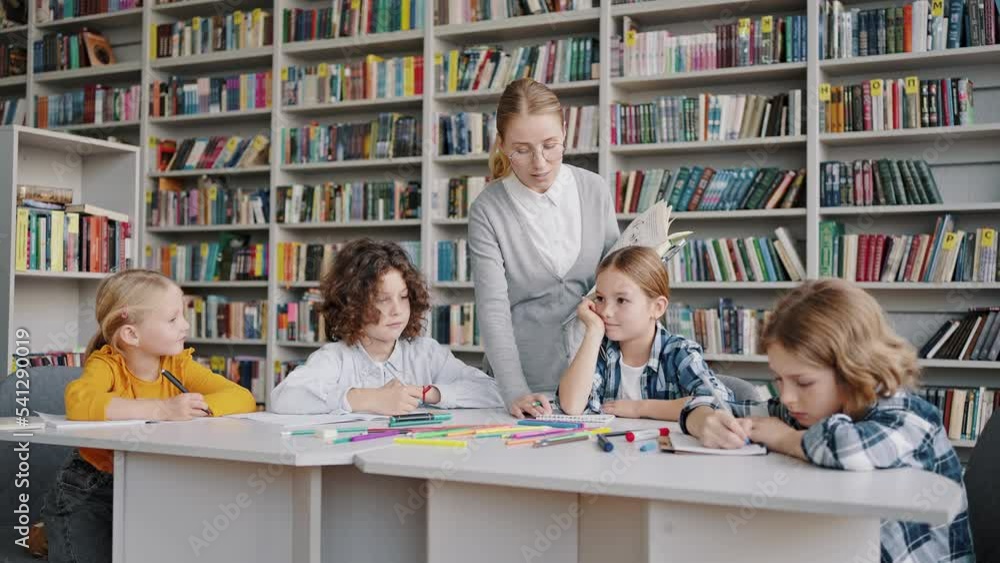 Teacher gives extracurricular classes for pupils in library Teacher gives extracurricular classes for pupils in library