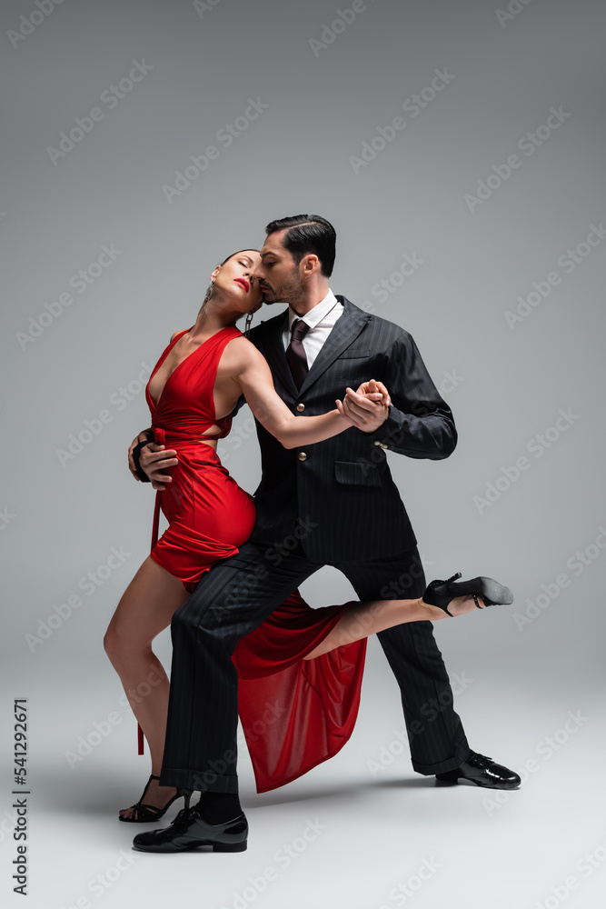 Full length of professional ballroom dancers performing tango on grey background Full length of professional ballroom dancers performing tango on grey background
