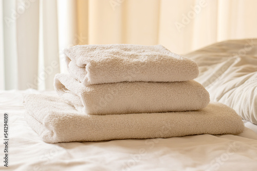 Clean towels on bed at hotel room. Bed maid-up with clean white pillows and bed sheets in beauty bedroom. Close-up