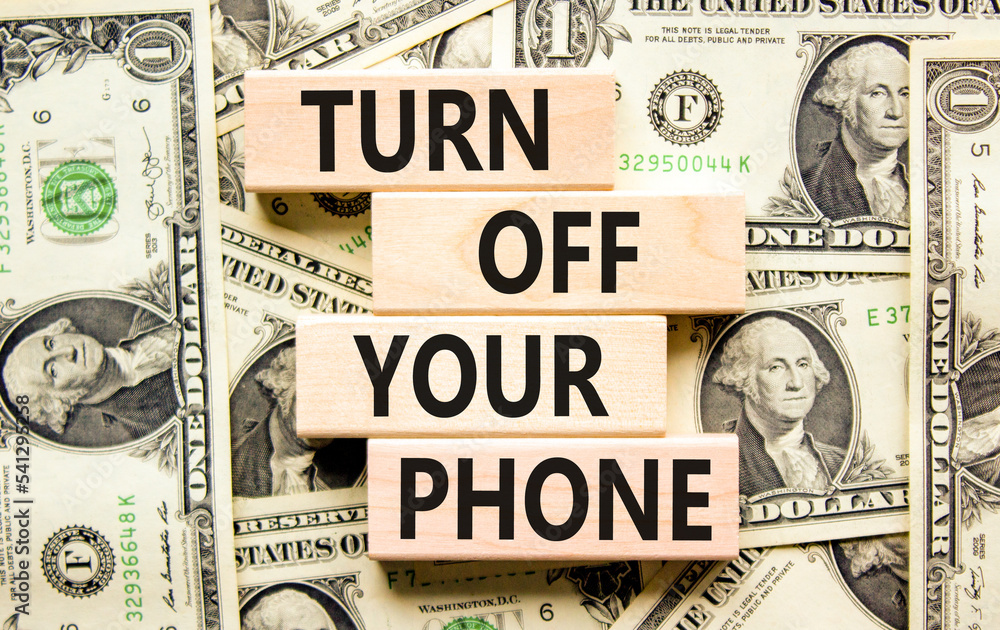 Turn off your phone symbol. Concept words Turn off your phone on wooden blocks. Beautiful background from dollar bills. Business, psychological turn off your phone concept. Copy space.
