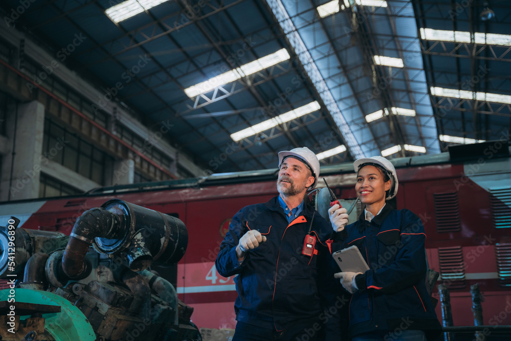 Professional Engineers are on duty, discussing, inspecting, and maintaining the machine in the train garage that is malfunctioning. Professional Engineers are on duty, discussing, inspecting, and maintaining the machine in the train garage that is malfunctioning.