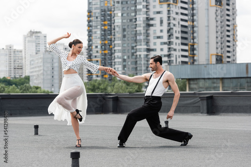 Side view of smiling dancers moving on roof of building outdoors © LIGHTFIELD STUDIOS